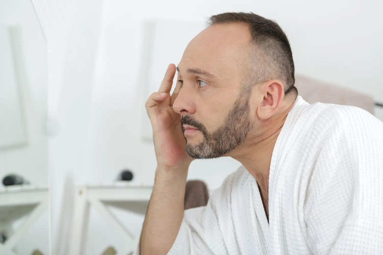 Reifer Mann, der sein Gesicht im Spiegel auf Falten untersucht