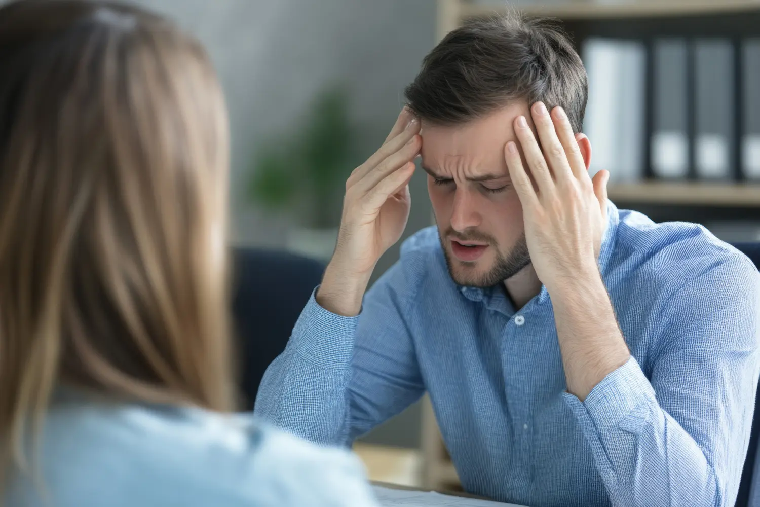 In einem Firmenbüro führt ein Psychologe ein Gespräch mit einem gestressten Mitarbeiter und bietet ihm Strategien zur Stressbewältigung und Unterstützung an.